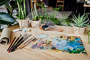 Table full of potted green plants, art supplies and vintage camera