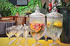 Glass pitchers with water flavored with various fruits and bowls on the table photo