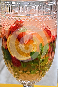 Water flavored with orange, strawberries and mint in the glass jug photo