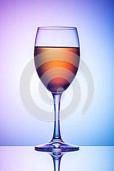 On the table is a glass of wine on a colored background