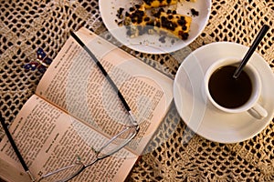 Table with glasses and a book next to a coffee with pastries