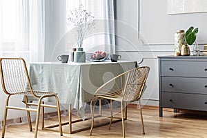 Table, golden chairs and grey commode in beautiful living room interior