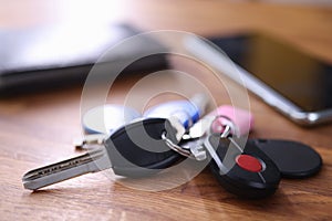 On table are keys with black remote control and red button