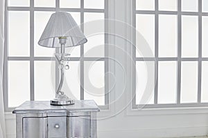 Table-lamp on bedside table against latticed photo