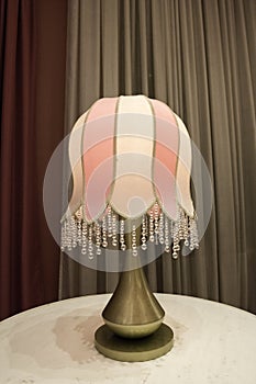 Table lamp, illuminated, classic art-deco style with brown curtain drapes behind