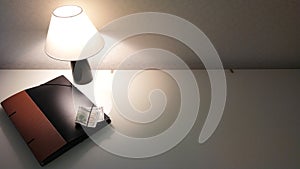 Table lamp with yellow light on a glass white table with a business folder with documents and money dollars and a smartphone