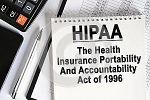 On the table lies a smartphone, a calculator and a notebook with the inscription- HIPAA