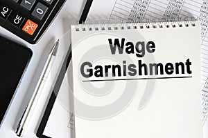 On the table lies a smartphone, a calculator and a notebook with the inscription- Wage Garnishment