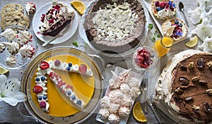 Table with loads of cakes, cupcakes, cookies, cakepops, desserts, fruits, flowers and orange juice