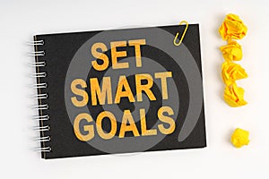 On the table is a marker, an exclamation mark and a notebook with the inscription - SET SMART GOALS