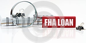 On the table is a notebook, a magnifying glass and a tablet with the inscription - FHA LOAN