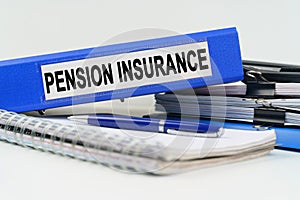 On the table are a notebook, a pen, documents and a folder with the inscription - PENSION INSURANCE