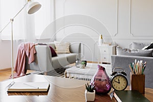 Table with notebook, small plant in pot, glass vase, clock and pencils in cup, real photo with copy space