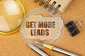 On the table are office items and a cardboard with the inscription - GET MORE LEADS