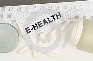 On the table is an open jar of pills and a sheet of paper with the inscription - E-Health