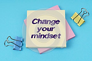 On the table are paper clips, note paper with text - Change your mindset
