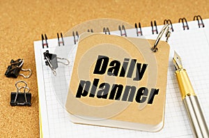 On the table is a pen and a notebook with the inscription - Daily planner