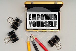 On the table are pencils and a business card holder, inside a business card with the inscription - EMPOWER YOURSELF