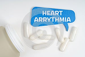 On the table are pills and a blue sign that says - Heart arrythmia