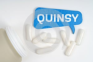 On the table are pills and a blue sign that says - quinsy photo