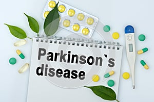 On the table are pills, a thermometer, leaves and a notebook with the inscription -Parkinsons disease