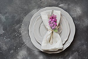 Table place setting with purple lilac flowers, silverware on vintage background. View from above. Copy space.