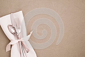 Table Place Setting with Silverware and White cloth napkin on Beige Brocade Tablecloth as the background with copy space.  It`s a