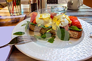 Table with plate with toast with egg, salmon and sauce