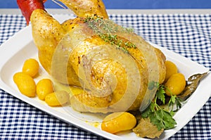 Table with a platter containing a roast chicken.