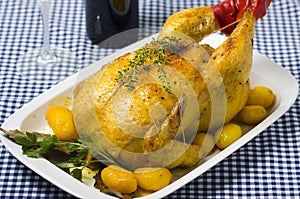 Table with a platter containing a roast chicken.