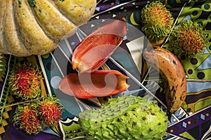 Table with pumpkin, rambutans, soursup and red banana. Still life composition with tropical fruits and vegetables.