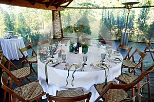 A table in the restaurant, decorated with decor, colored bottles with paws ate.An open veranda made of wood and stone