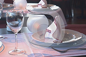 table in the restaurant with a tablecloth, silver forks, isolated knife, cloth napkins and crystal glasses. Ouerto