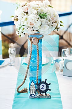 The table in the restaurant for a wedding in a marine style with fresh flowers and a table number in the form of an