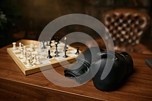Table in room with boxer gloves and chessboard with chesspieces, chess conflict