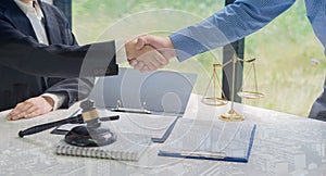 On a table with scales and hammers placed in front of the businessman shakes hands, making a deal with a lawyer. male judge legal