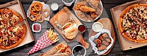 Table scene of assorted take out or delivery foods, top down view on a dark wood banner photo