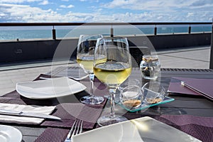 Table served for dinner on outside terrace with glasses of cold white wine and sea view