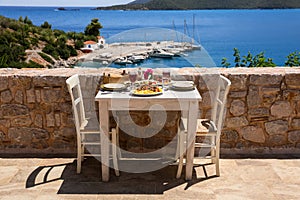 A table served for two with chicken souvlaki and french fries, greek salad, snacks and drinks on the summer terrace of the hotel r