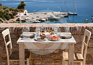 A table served for two with snacks and drinks on the summer terrace of the hotel room by the seascape.