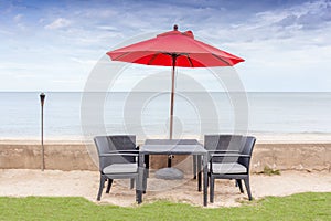 The table set, beach chairs and red umbrella with beautiful beach and blue sky background.