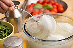 Table set with a bowl with buffalo mozzarella in the center and in the background the ingredients for the Mediterranean d