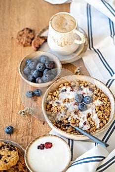 Table set with bowl of cereal topped with blueberries and yogurt, morning healthy breakfast