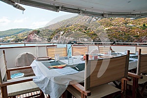 Table set for breakfast on the rear deck of a luxury private yacht, cruising the mediterranean sea and docked in front of Lipari