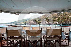 Table set for breakfast on the rear deck of a luxury private yacht, cruising the mediterranean sea and docked in front of Lipari