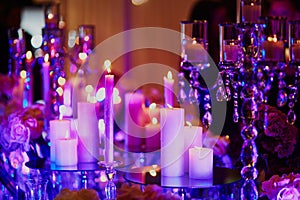 Table set with candles for a festive event, party or wedding reception, in purple light