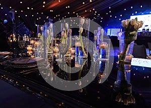 Table set with candles and tulip flowers decoration at night, indoor luxury wedding with low light romantic ambient photo