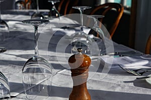 A table is set for dinner, glasses and white napkins with a wooden pepper grinder