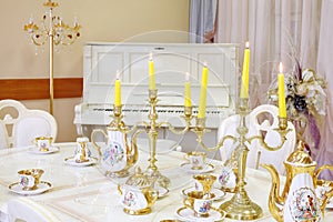 Table with set of porcelain dishes and candles in photo