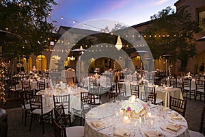 Table settiings for a large wedding ceremony in an outdoor patio area